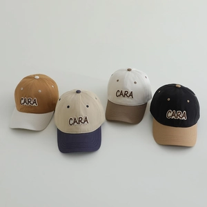 Detail of four color-block kids baseball caps with embroidered CARA lettering on front