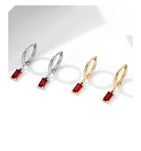Detail view of gold and silver stainless steel earrings with red rectangular zircon stones