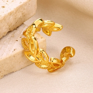 Macro shot of gold-plated leaf vine open ring displayed on textured stone background