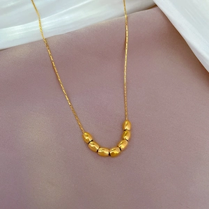 Close-up of gold titanium steel bead necklace on elegant silk background fabric