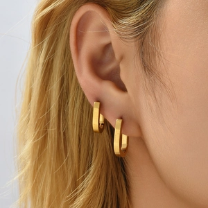 Macro side view of elegant matte 18K gold-plated oval geometric earrings on a model