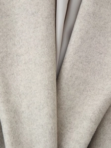 Close-up of light grey wool blend coat fabric showing detailed texture and premium stitching