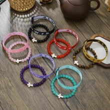 Detail of colorful beaded and W.W.J.D. woven bracelets with a white cross pendant charm