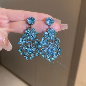 Close-up of vintage flower earrings with blue crystals and a starburst sparkle effect