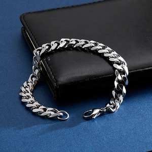 Silver Cuban link bracelet on black leather wallet with industrial metallic texture