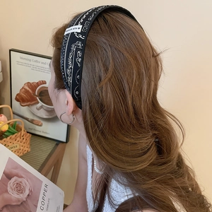 Détail d'un serre-tête en tissu cachemire noir avec étiquette faite main sur cheveux bruns