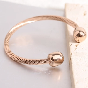 Detail of rose gold cable twist cuff bracelet on a minimalist textured stone background