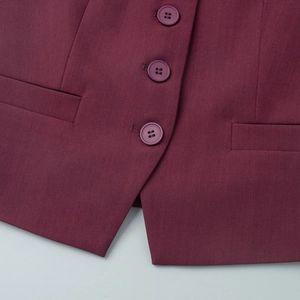 Close-up of burgundy vest showing three resin buttons, side pockets and V-shaped hem detail