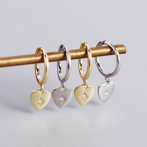 Detail of gold and silver heart earrings with starburst set crystals on a display bar