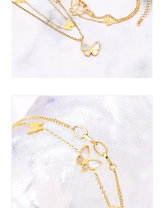 Detail of double-layer gold butterfly bracelet featuring white shell inlay and sleek chains