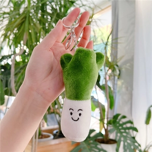 Detail of cute plush spring onion keychain with embroidered smile and silver metal clasp