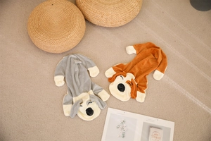 Flat lay of gray and brown plush dog jumpsuits on a beige rug with cozy home decor