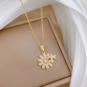Detailed close-up of a gold flower and dragonfly pendant necklace on jewelry box