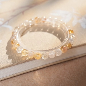 Bracelet en perles de cristal jaune avec un rétroéclairage doré chaud posé sur un livre