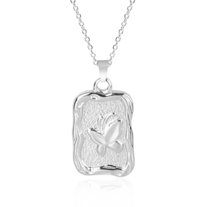 Macro view of silver butterfly relief on a textured rectangular pendant necklace