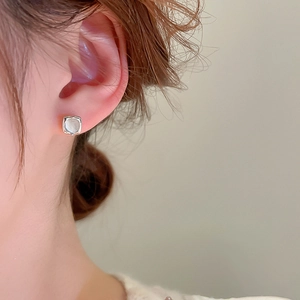 Detail view of a square faux cat eye stone earring on ear with silver finish