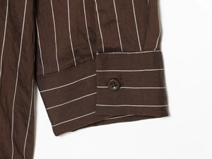 Detail of dark brown striped shirt cuff with matching resin button and fabric texture