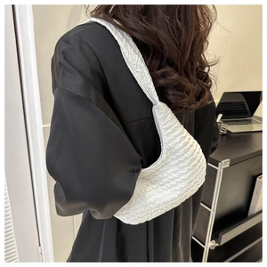 Detail showing white pleated cloud bag with bubble texture worn as a shoulder bag