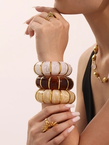 Detailed view of layered candy-colored resin bracelets with elegant golden metal spacers