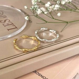 Detail of minimalist 925 silver heart rings in gold and silver finish on a book