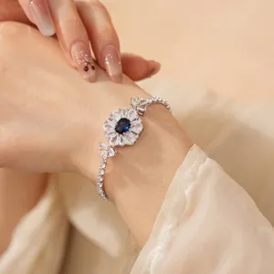 Elegant flower bracelet with blue oval zircon and pavé stones on a model's wrist