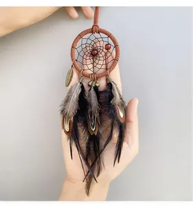 Detail of dreamcatcher car charm with brown feathers, beads and metallic leaf pendant