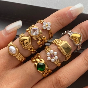 Golden watchband style ring set with heart, flower, and emerald cut zircon accents