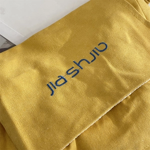 Detailed macro view of yellow canvas bag showing thick fabric texture and blue lettering