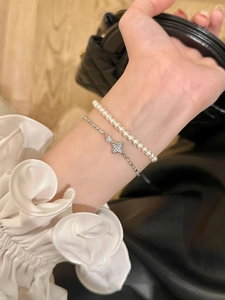 Close-up of double-layered bracelet with white pearls and a sparkling star pendant