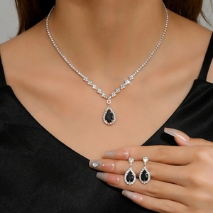 Detail of silver necklace and earring set with pear-shaped black stones and crystals