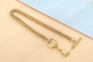 Detail eines goldenen zweilagigen Armbandes mit Gitarrenanhänger und OT-Verschluss