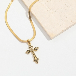 Macro view of gold cross pendant with cubic zirconia on flat snake chain over stone