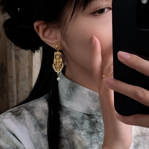 Macro side view of a geometric hollow gold earring with elegant pearls on a model
