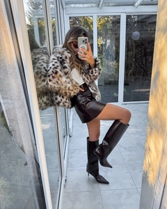 Selfie miroir montrant un manteau court en fausse fourrure léopard avec jupe et bottes en cuir