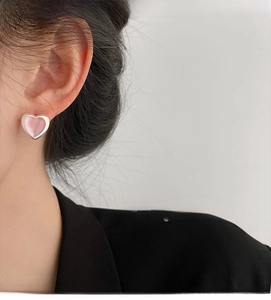 Close-up of pink heart earrings on model showing silver frame and textured detail