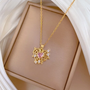 Luxurious gold necklace with spider web heart pendant and pink gemstone on silk background
