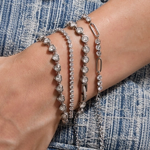 Set of silver stainless steel bracelets with zirconia stones on blue denim background