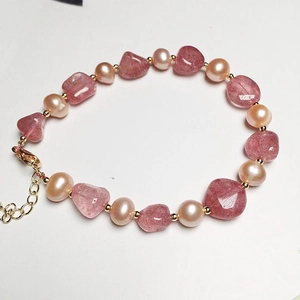 Detail of strawberry quartz beads and freshwater pearls on a gold plated chain bracelet