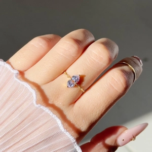 Detail of adjustable gold chain ring featuring double purple heart-shaped gemstones