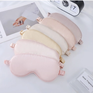 Close-up of five satin sleep masks in Morandi colors layered on a white textured fabric