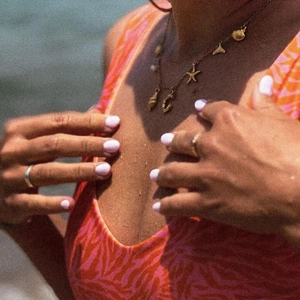 Close-up of a vintage steel necklace with seashell and starfish charms on a beach