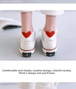 Close-up of white ankle socks featuring a 3D red heart detail on the heel with white sneakers