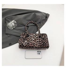 Detailed top view of a leopard print handbag with heart charm and everyday essentials