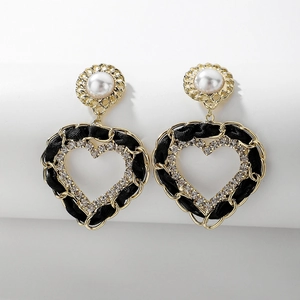 Détail de boucles d'oreilles en forme de cœur avec perles, strass et ruban noir en cuir