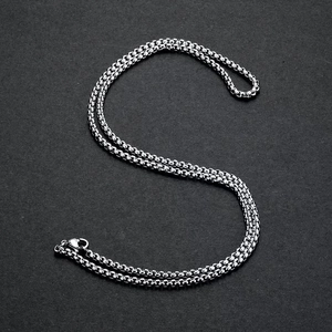 Detail of silver box chain necklace with sleek metallic luster on dark background