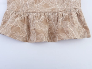 Detailed view of earth-tone embroidery and leaf pattern on wide-leg trousers hem
