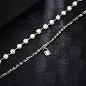 Detail view of double-layer necklace with white pearls and silver padlock pendant