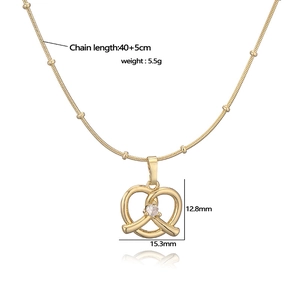Gold heart knot pendant necklace with zircon stone on white background with reflection