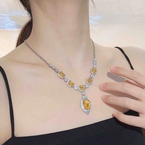 Detail of luxury yellow gemstone necklace with marquise pendant worn on neck