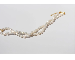 Detailed view of glossy cream pearls and golden clasp on a vintage style necklace